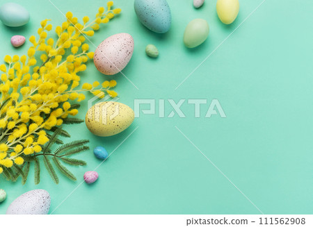 Festive Easter Decoration With Colorful Eggs and Mimosa Flowers on a Pastel Green Background 111562908