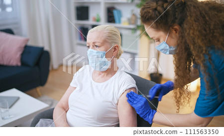 A medical worker administers a dose of the COVID-19 vaccine to a senior woman, prioritizing prevention in the elderly population 111563350