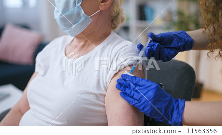 A nurse administers a vaccine injection to a mature woman in the nursing home, COVID-19 prevention awareness A nurse administers a vaccine injection to a mature woman in the nursing home, COVID-19 prevention awareness 111563356