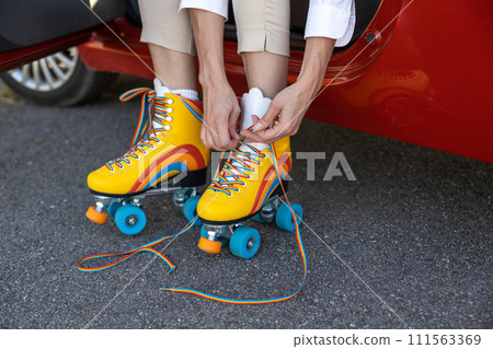 Woman wearing roller skates while sitting in her automobile 111563369