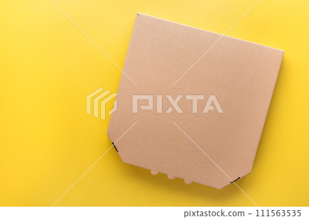 Pizza closed carton box on uniform yellow background flat lay mockup with blank space 111563535
