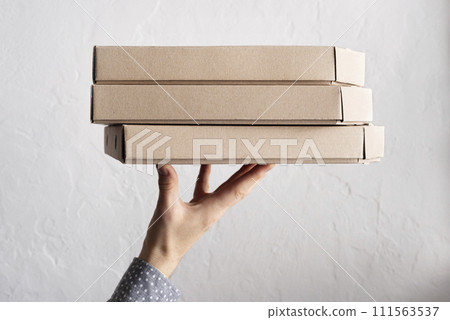 Caucasian male hands hold three pizza boxes side view with copy-space 111563537