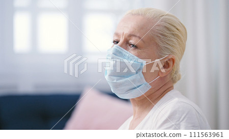 Upset mature woman in a protective face mask sitting lonely in a doctor's office hall Upset mature woman in a protective face mask sitting lonely in a doctor's office hall 111563961