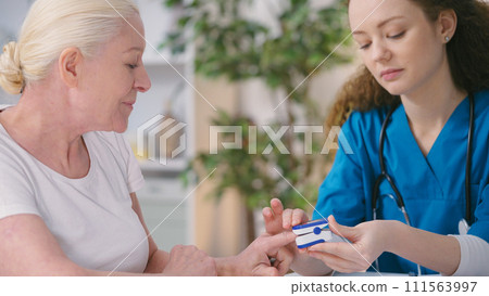 Female physician measuring senior woman's blood oxygen level, health check-up Female physician measuring senior woman's blood oxygen level, health check-up 111563997