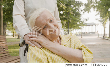 Grateful woman wheelchair user stroking husband's hand, family values, kindness 111564277