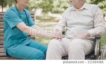 Caring nurse holding patient's hand, support during rehabilitation in clinic 111564366