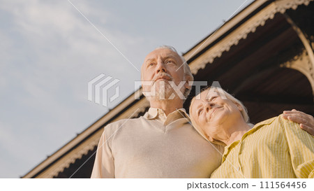 Retired couple hugging and looking into distance, happy marriage, social security 111564456