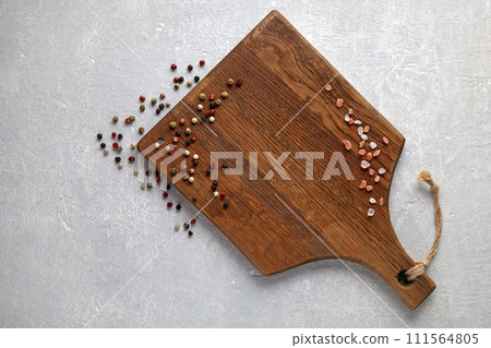 scattered peppercorns and pink salt on a brown wooden cutting board on a white stone table scattered peppercorns and pink salt on a brown wooden cutting board on a white stone table 111564805