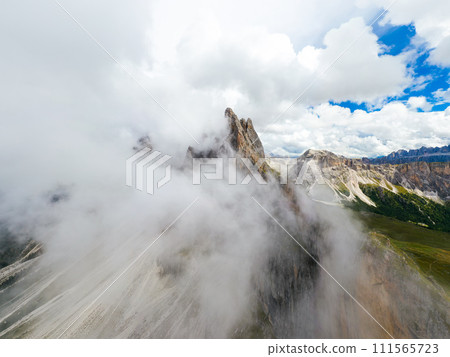 Dense fog covered rocky peak of Seceda mountain in touristic Italian Alps. Observation point overlooking ridgeline on cloudy day aerial view 111565723