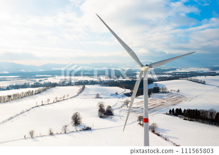 Wind mills or wind turbines in the field in winter with mountains on the background. 111565803