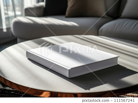 Advertising close up mockup shot of book lying on white coffee table with white sofa and sun rays at the background 111567241