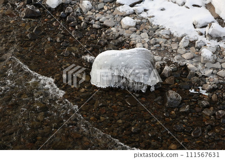 The shape of stones on the shore of a lake frozen by ice 111567631