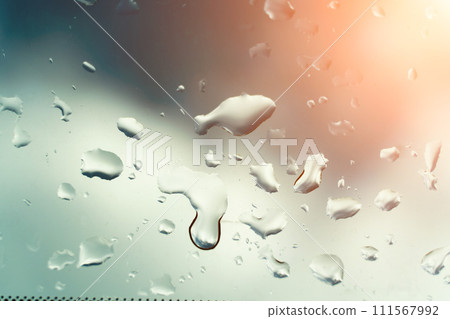 Water drops on glass against blue sky, rainy season concept. Window view background screensaver 111567992