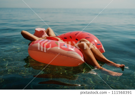 Summer vacation woman in hat floats on an inflatable donut mattress. Happy woman relaxing and enjoying family summer travel holidays travel on the sea. Summer vacation woman in hat floats on an inflatable donut mattress. Happy woman relaxing and enjoying family summer travel holidays travel on the sea. 111568391