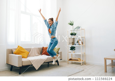 Joyful Woman Jumping and Dancing to Music in Home Apartment, Carefree and Happy 111569224
