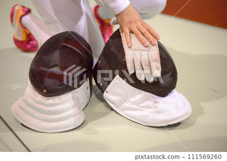 fencing equipment, white gloves and protective helmets with  mesh on the face 111569260