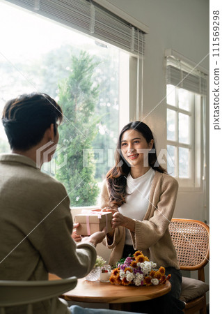 Romantic young asian couple embracing giving present in living room at home. Fall in love. Valentine concept 111569298