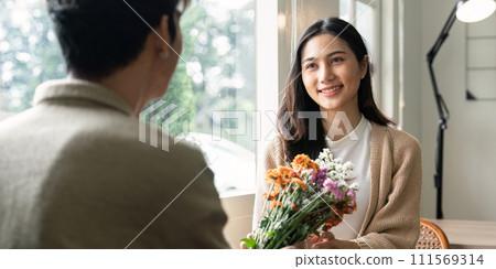 Romantic young asian couple embracing with holding flowers and smiling in living room at home. fall in love. Valentine concept 111569314