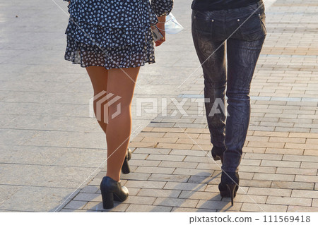 Women's legs in stockings and jeans. Easy walk along the pavement Women's legs in stockings and jeans. Easy walk along the pavement 111569418