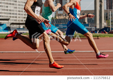 three male athletes sprinting on red track, muscles taut, competing fiercely. Brightly colored shoes emphasize motion three male athletes sprinting on red track, muscles taut, competing fiercely. Brightly colored shoes emphasize motion 111570812