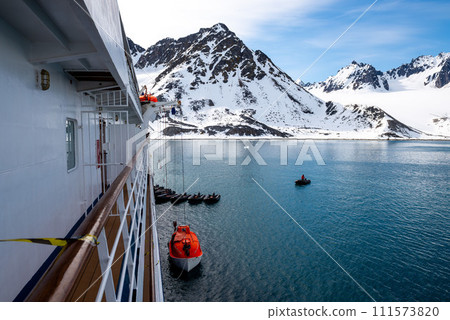 Lowering orange lifeboat to water in Arctic waters, Svalbard. Abandon ship drill. Lifeboat training. Man over board drill. Lowering orange lifeboat to water in Arctic waters, Svalbard. Abandon ship drill. Lifeboat training. Man over board drill. 111573820