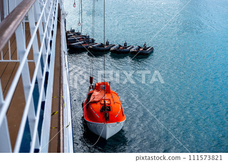 Lowering orange lifeboat to water in Arctic waters, Svalbard. Abandon ship drill. Lifeboat training. Man over board drill. Lowering orange lifeboat to water in Arctic waters, Svalbard. Abandon ship drill. Lifeboat training. Man over board drill. 111573821