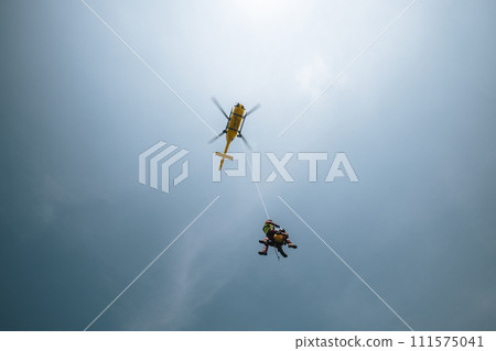 Paramedics hanging on rope under rescue helicopter. Paramedics hanging on rope under rescue helicopter. 111575041
