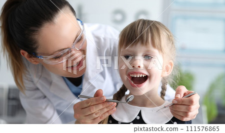 Woman dentist examines teeth in clinic at child Woman dentist examines teeth in clinic at child 111576865