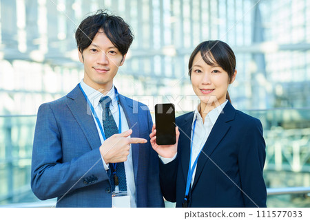 Men and women in suits showing smartphone screens Men and women in suits showing smartphone screens 111577033