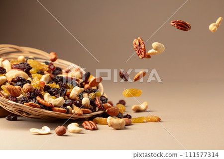 Flying dried fruits and nuts on a beige background. 111577314