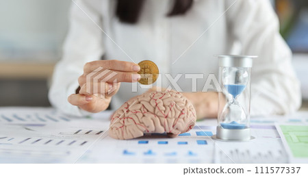 Business woman holding bitcoin coin in front of brain mockup and hourglass closeup Business woman holding bitcoin coin in front of brain mockup and hourglass closeup 111577337