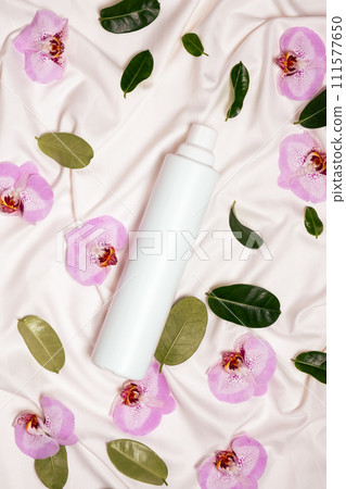 Fabric softener with floral scent among flowers on bed linen top view. 111577650