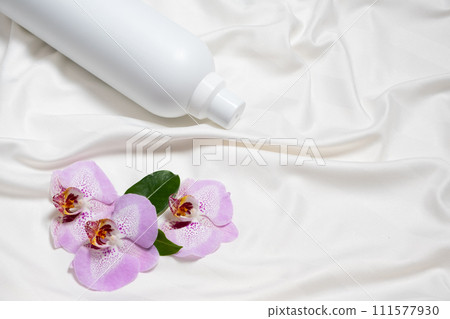 Natural fabric softener on satin fabric with orchid flowers, space for text Natural fabric softener on satin fabric with orchid flowers, space for text 111577930