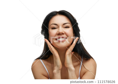 Portrait of cheerful woman with hands touching chin, looking at camera against white studio background. Portrait of cheerful woman with hands touching chin, looking at camera against white studio background. 111578026