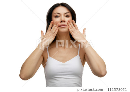 Middle aged woman doing facial massage improving skin tone and elasticity, stimulating its renewal against white studio background. 111578051