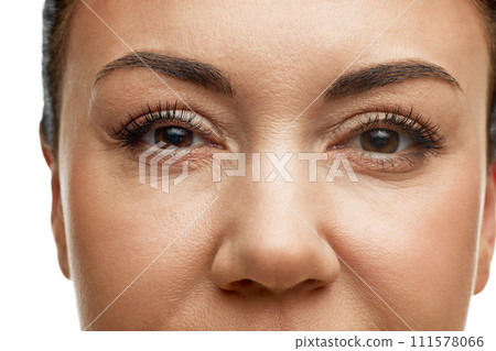 Cropped portrait of 40s years old woman with well kept shiny skin against white studio background. Model squints and wrinkles stand out. Anti-aging 111578066