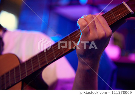 Close up photo of young man, music artist, blogger playing guitar while holds online streaming or record video-lesson. 111578069
