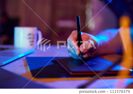 Male hand drawing on digital drawing pad in vibrant, illuminated workspace. Content creator and creative occupation. Male hand drawing on digital drawing pad in vibrant, illuminated workspace. Content creator and creative occupation. 111578379