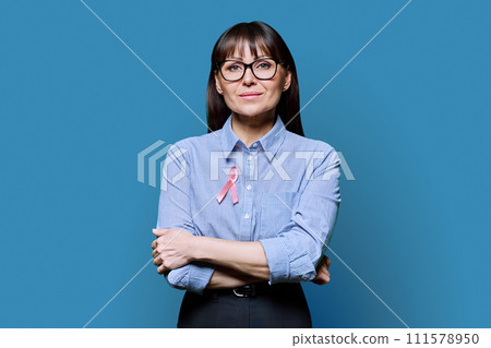 Middle-aged woman with pink ribbon symbolizing International Breast Cancer Day 111578950