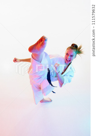Top view portrait of female karate fighter, teacher performing high kick isolated over white studio background. 111579632
