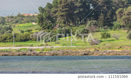Modern golf courses for tourists with clear ponds and palm trees for relaxation and golf timelapse. Lagos, Portugal, Algarve. Modern golf courses for tourists with clear ponds and palm trees for relaxation and golf timelapse. Lagos, Portugal, Algarve. 111581066