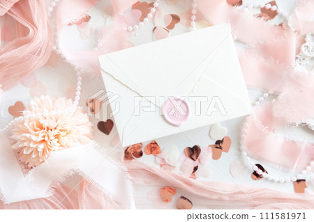 Sealed envelope near pink decorations, hearts and silk ribbons on white table top view, mockup 111581971