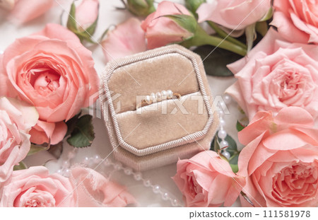 Engagement ring in a abox between light pink roses and buds close up, wedding concept 111581978