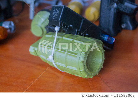 Prototype model of grenade ammunition printed on 3D printer. Small models of grenade defensive weapon printed on 3D printer from molten plastic on table. New modern innovation printing technology Prototype model of grenade ammunition printed on 3D printer. Small models of grenade defensive weapon printed on 3D printer from molten plastic on table. New modern innovation printing technology 111582002
