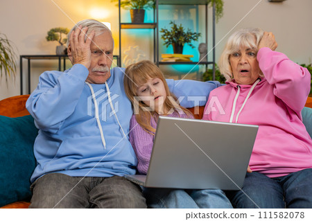 Upset grandfather grandmother and granddaughter playing game on laptop and losing fail at home sofa 111582078