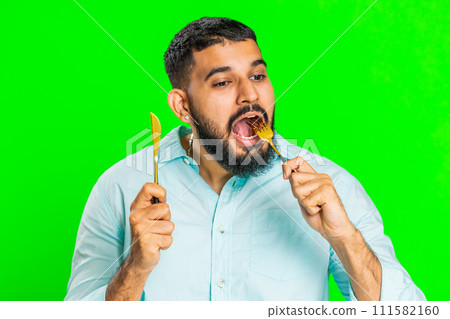 Hungry man waiting for serving dinner meal dishes with restlessness holding cutlery fork knife 111582160