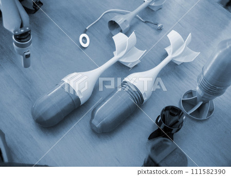 Prototype model of rocket bomb tip printed on 3D printer. Small models of tail fins, tail cone printed on 3D printer from molten plastic. Military weapons. New modern innovation printing technology 111582390
