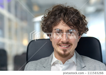 Professional young male with curly hair showcasing confidence and expertise in a corporate office environment. Professional young male with curly hair showcasing confidence and expertise in a corporate office environment. 111583266