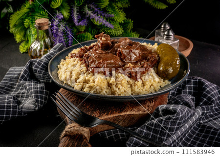 Chunky beef stew with savory sauce, served with bulgur groats. 111583946