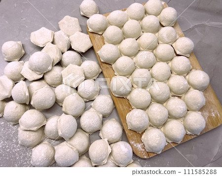 Dumplings made of dough and minced meat are stuck on the board 111585288
